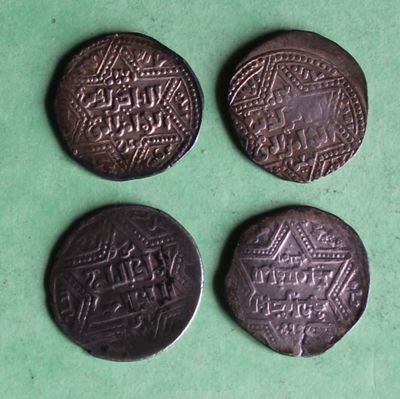 three old coins with designs on them on a green surface