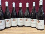six bottles of wine are lined up on a wooden table