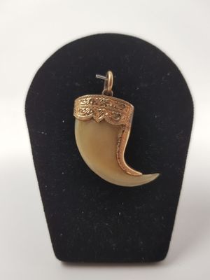a close up of a gold plated pendant on a black stand