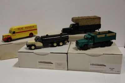 trois camions miniatures posés sur des cartons posés sur une table