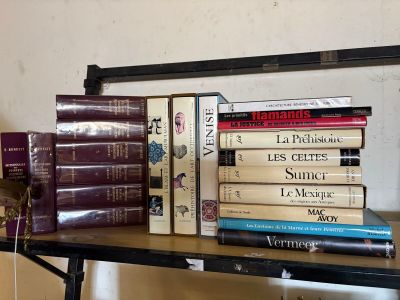 de nombreux livres posés sur une étagère à côté d'une horloge