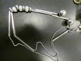 a silver necklace with beads and a chain on a table