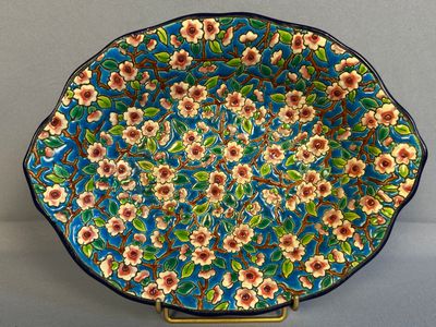 une assiette bleue ornée de fleurs, posée sur un socle