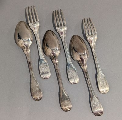 six fourchettes et cuillères sont alignées sur une table