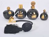quatre bouteilles noires ornées de motifs dorés et une boule noire surmontée d'un pompon noir