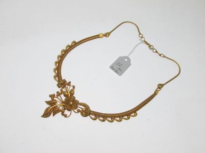 une image représentant un collier en or posé sur une surface blanche