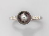 gros plan d'une bague en perles et diamants sur une surface blanche