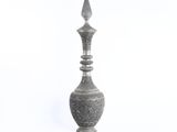 un vase en argent posé sur une surface blanche