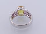 a close up of a ring with a yellow stone surrounded by pink stones