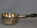 a silver saucepan with a wooden handle on a table