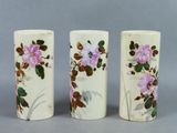 three white vases with pink flowers on them sitting next to each other