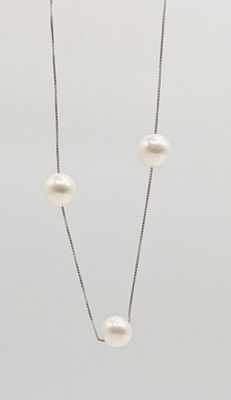 un gros plan d'un collier de perles blanches monté sur une chaîne en argent