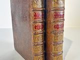 an old pair of books sitting on top of each other on a table