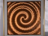 une image marron et blanche représentant un motif en spirale, dans un cadre en bois