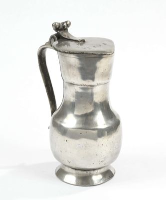 an antique silver pitcher on a white background with a bird on the handle