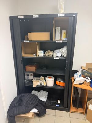 une bibliothèque noire sur laquelle sont posés de nombreux objets, dans une pièce