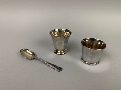 deux tasses en argent et une cuillère posées sur une table