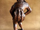wooden statue of a man with a hat and a bag on his back