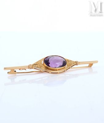 a close up of a gold broochle with a purple stone