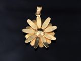 a close up of a gold flower pendant on a black surface
