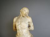 marble statue of a male torsoed figure on a marble pedestal