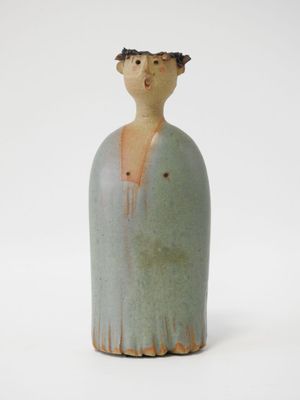 une petite figurine en céramique représentant une femme coiffée d'un chapeau
