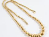 a gold beaded necklace on a white background