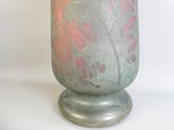 un vase vert orné d'un motif de feuilles rouges