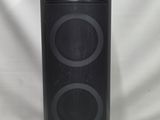 une enceinte noire posée sur une table, à côté d'un fond blanc