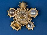 an image of a gold broochle with pearls on a blue background