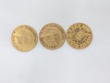 three different types of gold coins sitting on top of a white surface