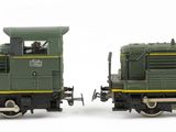 two toy trains sitting side by side on a white surface