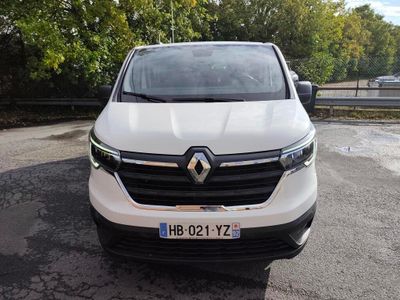 une camionnette blanche garée sur un parking avec des arbres en arrière-plan