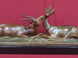 sculpture en bronze représentant deux cerfs couchés, posée sur un socle en bois
