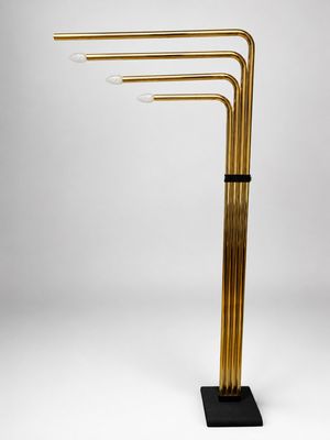 une lampe en laiton à trois branches avec un socle noir sur fond blanc
