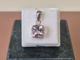 sterling silver pendant with a pink stone in a box on a marble surface