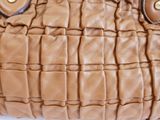 a close up of a brown purse on a white surface