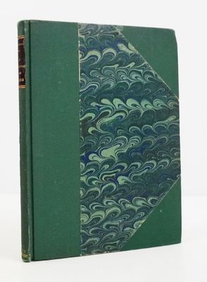 un vieux livre à la couverture verte posé sur une table blanche