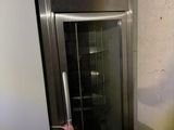 un petit réfrigérateur dans un coin de la pièce, muni d'une porte vitrée