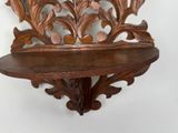 a wooden shelf on the wall with a decorative design
