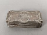 an antique silver cigarette case with ornate design on the front