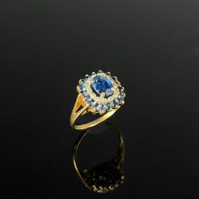 une bague en or sertie d'un saphir bleu et de diamants, sur un fond noir
