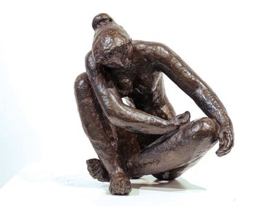 a bronze statue of a man sitting on a white surface