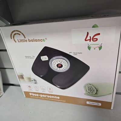 une boîte sur laquelle est dessinée une balance, posée sur une étagère