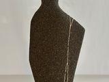 a black vase sitting on a table with a white background