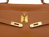a close up of a brown handbag with two gold handles
