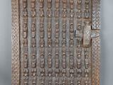 une vieille porte en bois ornée de sculptures sur une surface grise