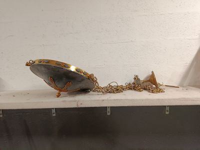 a silver and gold object on a shelf next to a white wall