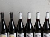 six bottles of wine are lined up on a wooden table