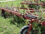 a tractor that is sitting in the grass with a planter attached to it